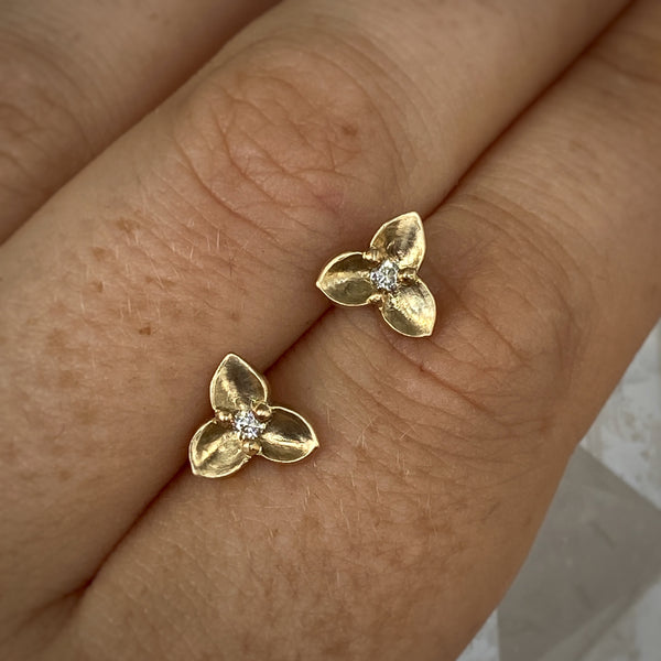 Myth and Stone Trillium studs in gold with diamonds on hand